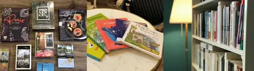 Verschiedene gebundene Bücher, Notizbücher und Postkarten auf einem Tisch gestapelt, teilweise mit farbigen Umschlägen und Illustrationen.