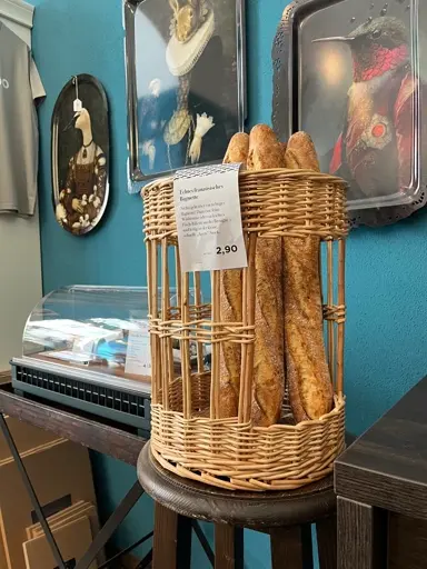 Wicker-Korb mit goldbraunen, länglichen Brotstangen oder Baguettes.