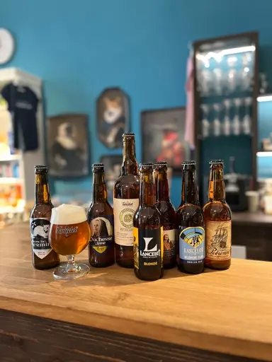 Verschiedene Bierflaschen und ein Glas mit goldbraunem Bier auf einem Tisch.