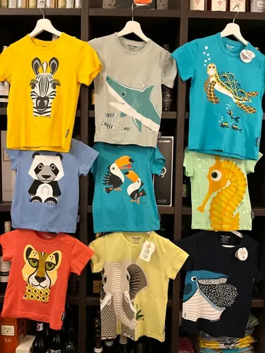 Bunte Kinder-T-Shirts mit Tiermotiven wie Zebra, Panda, Seepferdchen, Seepferd, Schildkröte und Flamingo auf Haken.