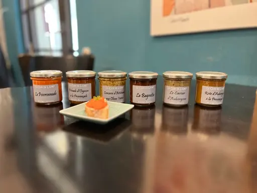 Fünf kleine Gläser mit verschiedenen goldbraunen bis orangefarbenen Aufstrichen auf schwarzem Tisch.