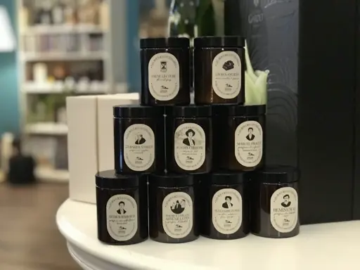 Schwarze Glasbehälter mit weißen Etiketten, verschiedene Deckelformen, enthalten feste oder flüssige Inhalte.