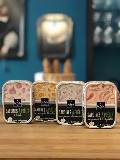Vier Konservendosen mit verschiedenen Gewürzmischungen für gegrillte Sardinen auf Holzregal.