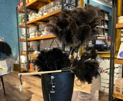Schwarze Federbüsche in verschiedenen Größen in einem schwarzen Topf mit Holzunterlage.